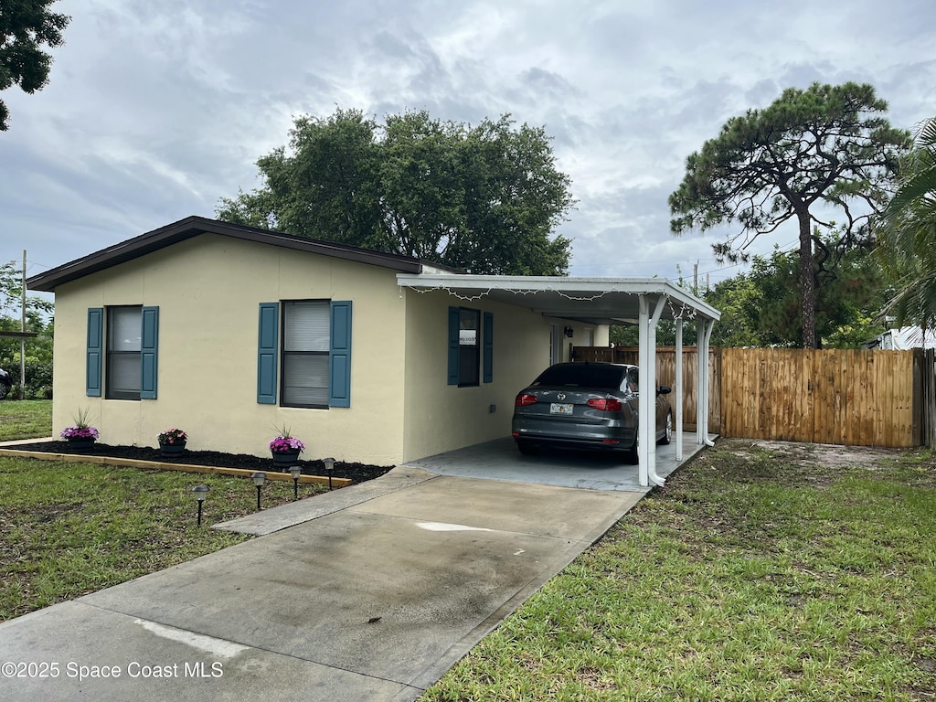 1148 Indrio Ln NE, Palm Bay, FL 32905 - view of front of property featuring concrete driveway, an attached carport, and stucco siding