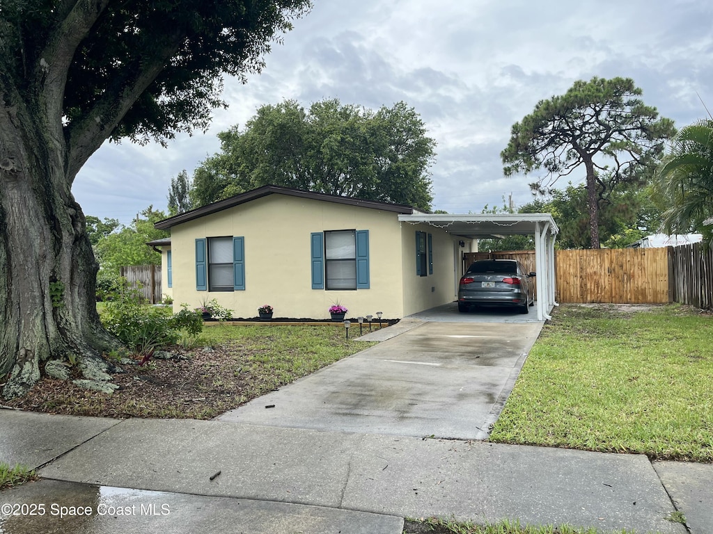 1148 Indrio Ln NE, Palm Bay, FL 32905 - single story home with concrete driveway, an attached carport, and stucco siding