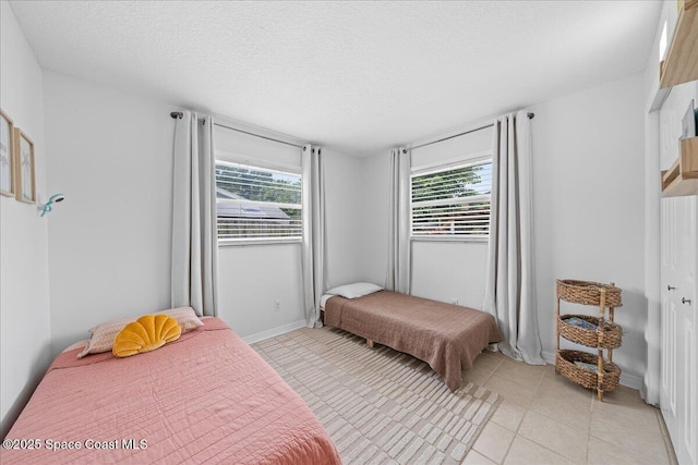 609 Tallwood Cir, Melbourne, FL 32904 - bedroom with multiple windows, light tile patterned floors, a textured ceiling, and baseboards