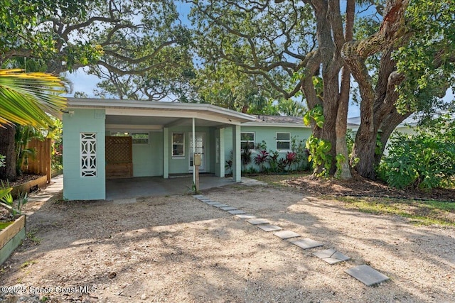 143 Cedar Ave, Cocoa Beach, FL 32931 - back of house with dirt driveway, a carport, and concrete block siding
