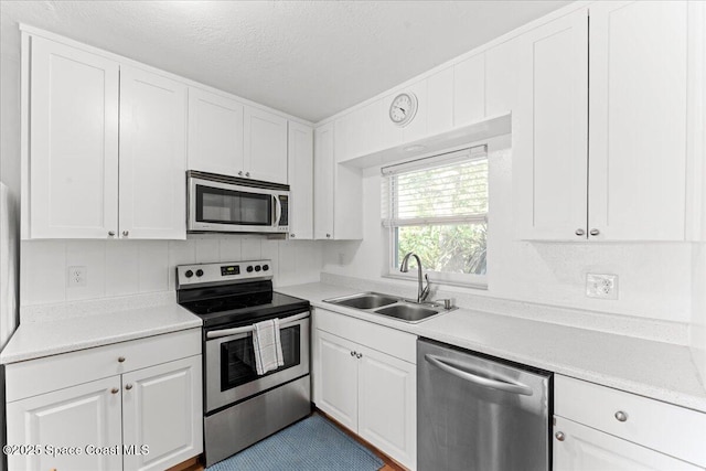 143 Cedar Ave, Cocoa Beach, FL 32931 - kitchen with stainless steel appliances, a sink, white cabinetry, and a textured ceiling