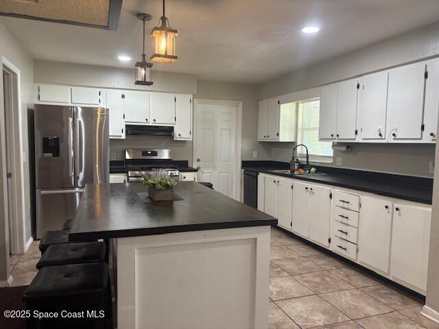 2109 Ivy Dr, Cocoa, FL 32922 - kitchen featuring stainless steel appliances, dark countertops, a sink, light tile patterned floors, and white cabinetry