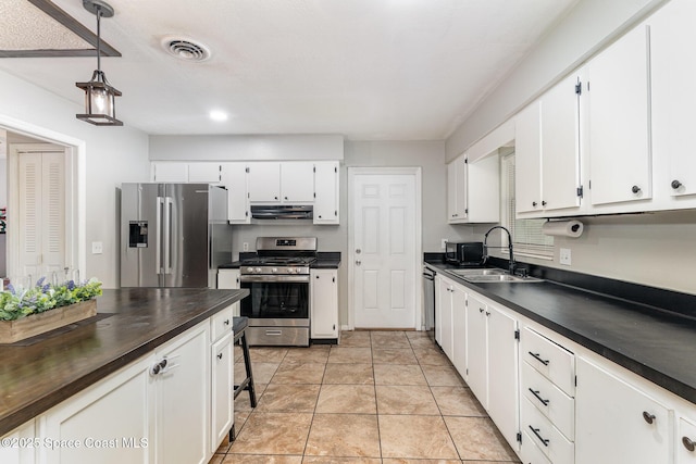 2109 Ivy Dr, Cocoa, FL 32922 - kitchen featuring stainless steel appliances, under cabinet range hood, a sink, white cabinetry, and pendant lighting