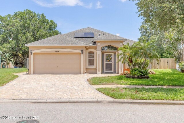 4843 Erin Ln, Melbourne, FL 32940 - view of front of house with stucco siding, decorative driveway, a garage, solar panels, and roof with shingles
