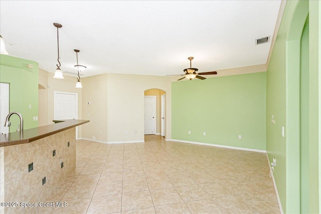 4843 Erin Ln, Melbourne, FL 32940 - kitchen featuring arched walkways, light tile patterned floors, ceiling fan, pendant lighting, and baseboards