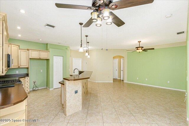 4843 Erin Ln, Melbourne, FL 32940 - kitchen featuring ceiling fan, dark countertops, arched walkways, cream cabinets, and light tile patterned floors