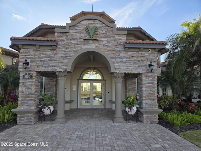 7690 Kerrington Dr, Melbourne, FL 32940 - doorway to property featuring french doors, a tiled roof, stucco siding, and stone siding