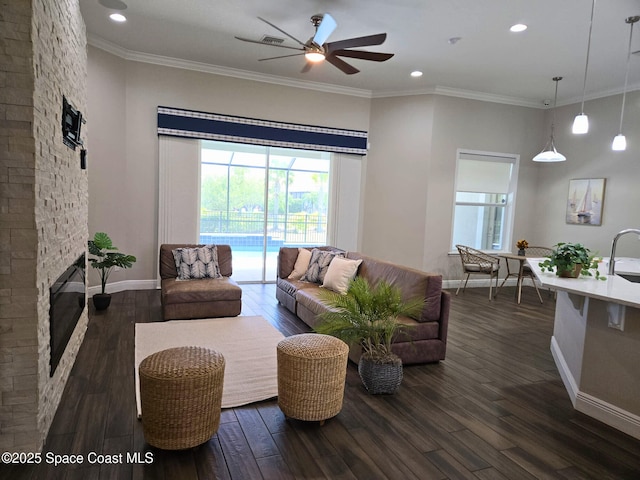 7690 Kerrington Dr, Melbourne, FL 32940 - living area featuring ceiling fan, dark wood-style flooring, a stone fireplace, recessed lighting, and crown molding