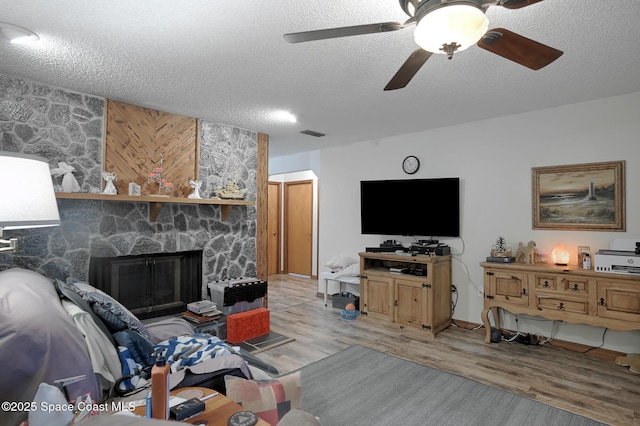 1387 Gleneagles Ct, Rockledge, FL 32955 - living area with a textured ceiling, light wood finished floors, a stone fireplace, and ceiling fan