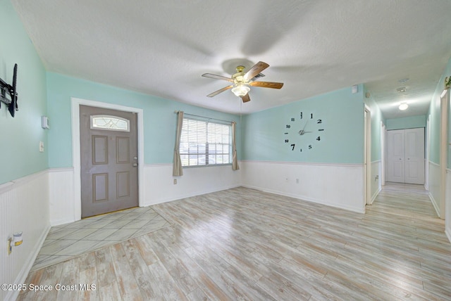 581 Howe Ave SE, Palm Bay, FL 32909 - entrance foyer featuring wainscoting, light wood-type flooring, a textured ceiling, and a ceiling fan