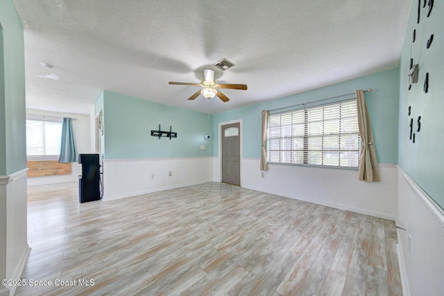 581 Howe Ave SE, Palm Bay, FL 32909 - unfurnished room featuring wainscoting, ceiling fan, light wood finished floors, and a textured ceiling
