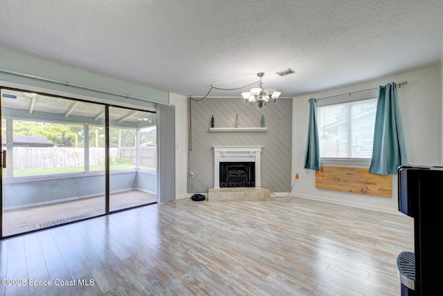 581 Howe Ave SE, Palm Bay, FL 32909 - unfurnished living room with a chandelier, wood finished floors, a textured ceiling, a fireplace with raised hearth, and wooden walls