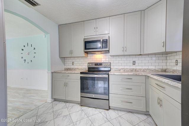 581 Howe Ave SE, Palm Bay, FL 32909 - kitchen featuring stainless steel appliances, a textured ceiling, light marble finish floors, a sink, and decorative backsplash