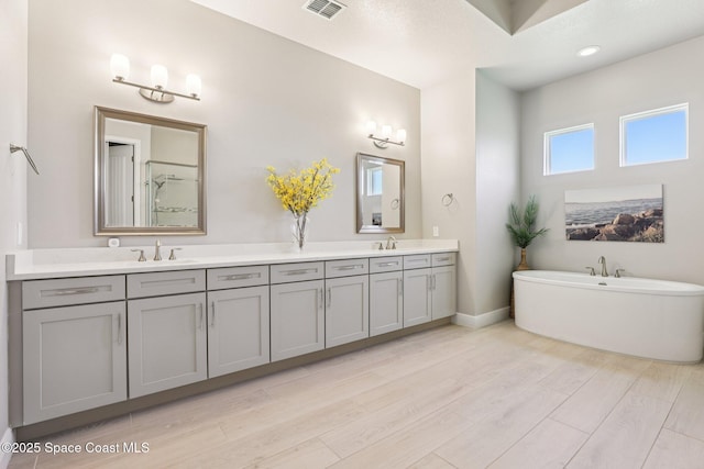1025 Aranceto Cir, Merritt Island, FL 32952 - bathroom with double vanity, a freestanding tub, a shower, and wood finished floors