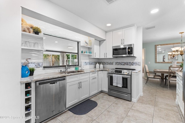 715 Atlantic Dr, Satellite Beach, FL 32937 - kitchen with open shelves, appliances with stainless steel finishes, white cabinets, light stone counters, and light tile patterned flooring