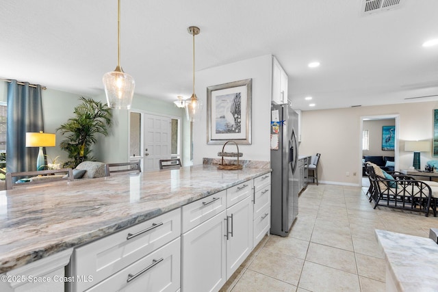 715 Atlantic Dr, Satellite Beach, FL 32937 - kitchen featuring stainless steel fridge, white cabinetry, light stone countertops, hanging light fixtures, and light tile patterned floors