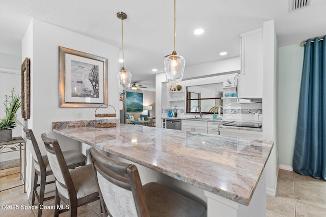715 Atlantic Dr, Satellite Beach, FL 32937 - kitchen featuring dishwasher, white cabinetry, a kitchen breakfast bar, light stone countertops, and recessed lighting