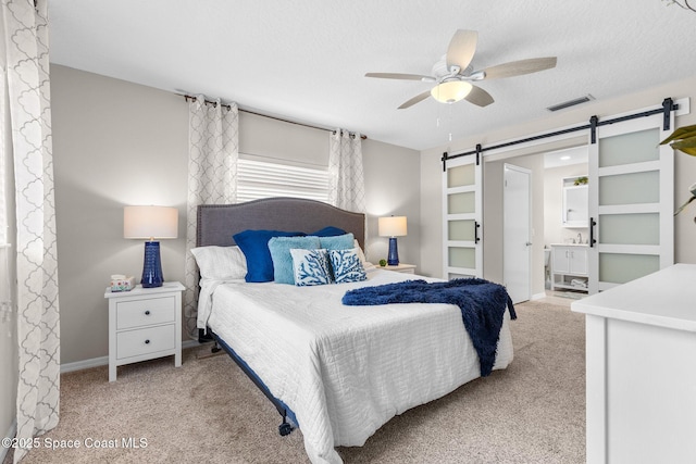 715 Atlantic Dr, Satellite Beach, FL 32937 - bedroom with a barn door, light carpet, ensuite bath, and a ceiling fan