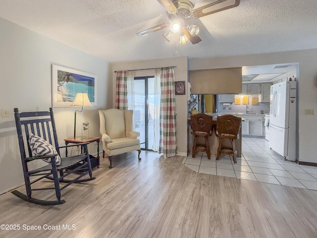 1395 Angler St, Merritt Island, FL 32952 - living area with a textured ceiling, light wood-style floors, ceiling fan, and baseboards