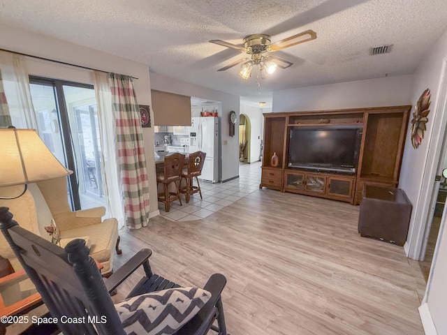 1395 Angler St, Merritt Island, FL 32952 - living room with light wood-style flooring, arched walkways, a ceiling fan, and a textured ceiling