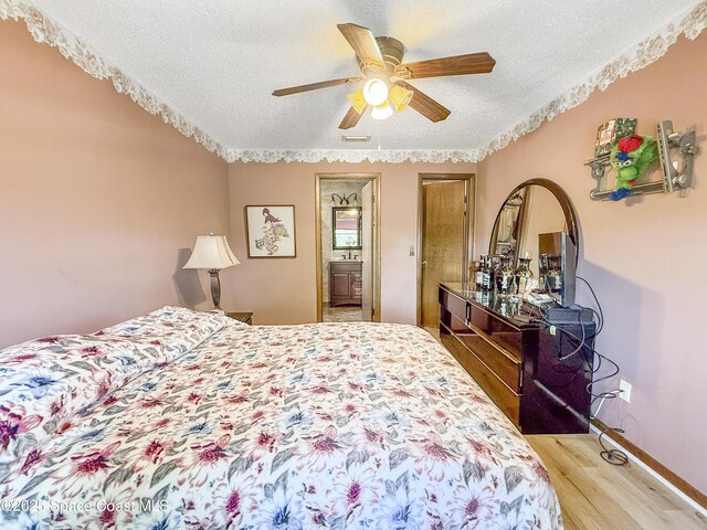 1395 Angler St, Merritt Island, FL 32952 - bedroom featuring a textured ceiling, light wood finished floors, a ceiling fan, connected bathroom, and baseboards