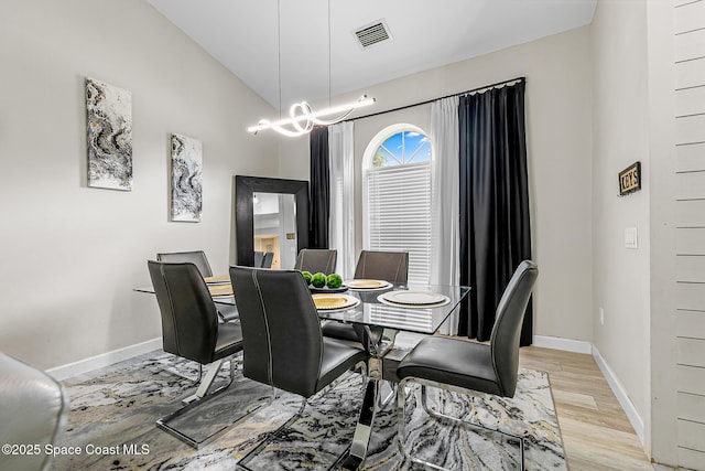 4236 Pondapple Dr, Titusville, FL 32796 - dining area featuring baseboards, a chandelier, vaulted ceiling, and light wood finished floors
