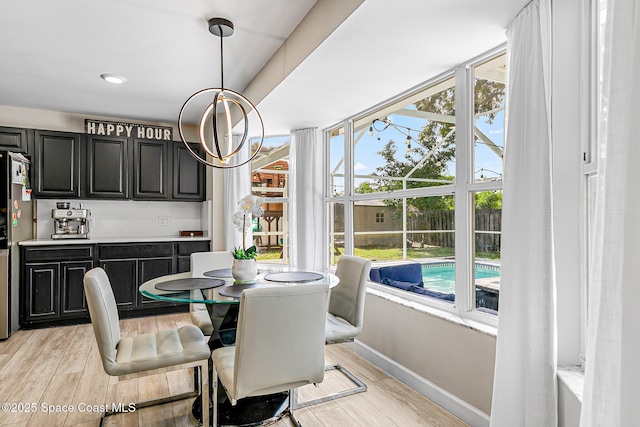 4236 Pondapple Dr, Titusville, FL 32796 - dining area featuring light wood-style flooring, baseboards, a chandelier, and bar