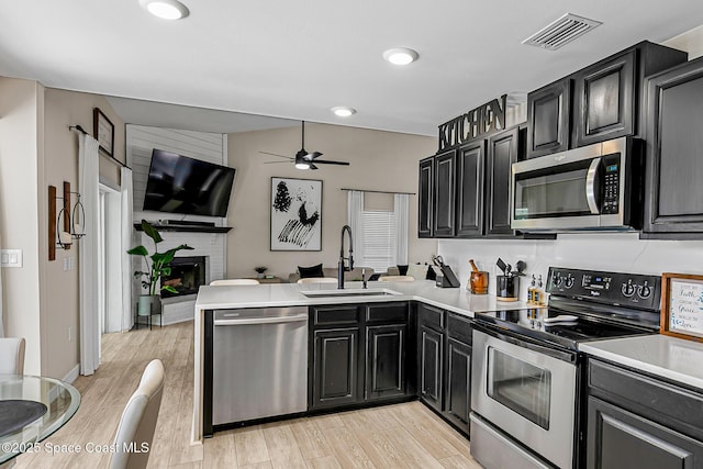 4236 Pondapple Dr, Titusville, FL 32796 - kitchen with appliances with stainless steel finishes, a sink, a peninsula, ceiling fan, and dark cabinets
