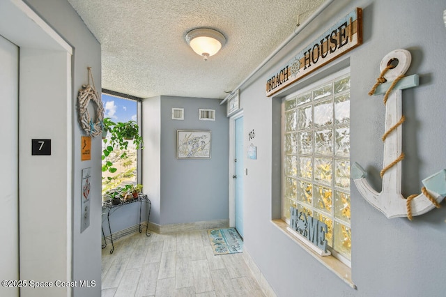 3221 S Atlantic Ave Unit 703, Cocoa Beach, FL 32931 - doorway to outside featuring a textured ceiling, wood finished floors, and baseboards