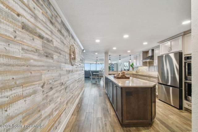 3221 S Atlantic Ave Unit 703, Cocoa Beach, FL 32931 - kitchen featuring appliances with stainless steel finishes, wall chimney exhaust hood, light countertops, light wood-style floors, and a kitchen island