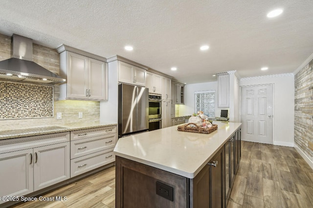 3221 S Atlantic Ave Unit 703, Cocoa Beach, FL 32931 - kitchen with wall chimney exhaust hood, stainless steel appliances, light wood-style flooring, tasteful backsplash, and recessed lighting