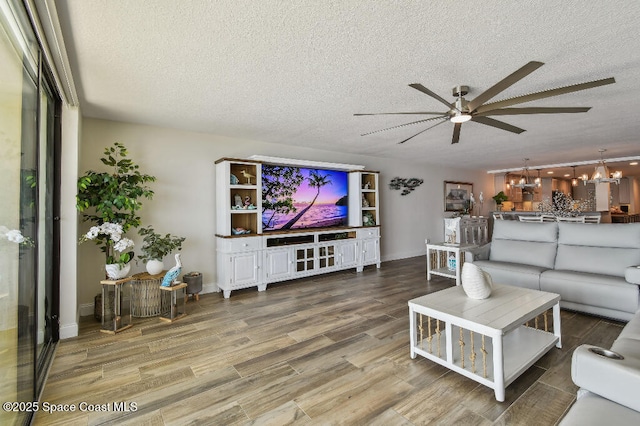 3221 S Atlantic Ave Unit 703, Cocoa Beach, FL 32931 - living room featuring ceiling fan, a textured ceiling, wood finished floors, a chandelier, and baseboards
