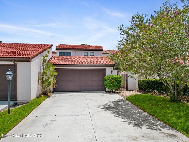 105 Osprey Ct, Melbourne, FL 32940 - mediterranean / spanish-style house featuring stucco siding, an attached garage, a tiled roof, driveway, and a gate