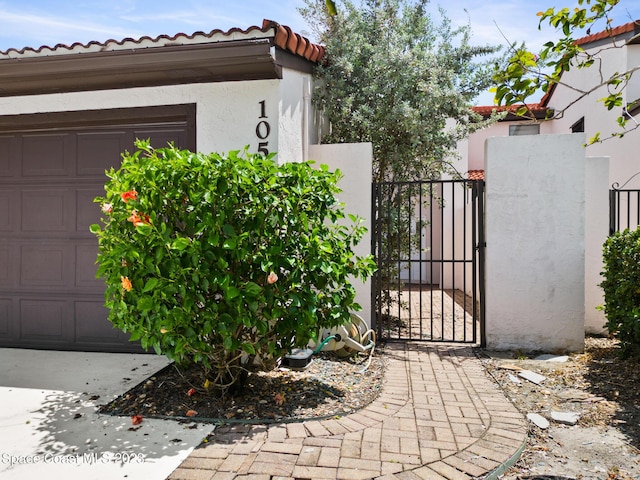 105 Osprey Ct, Melbourne, FL 32940 - view of home's exterior with a gate, stucco siding, a tile roof, and an attached garage