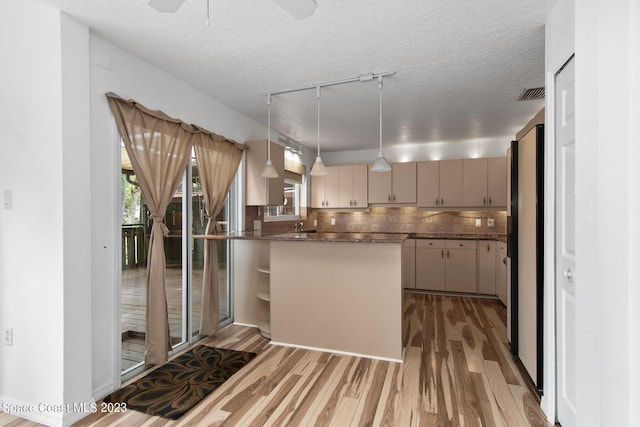 105 Osprey Ct, Melbourne, FL 32940 - kitchen with wood finished floors, a peninsula, a textured ceiling, pendant lighting, and tasteful backsplash