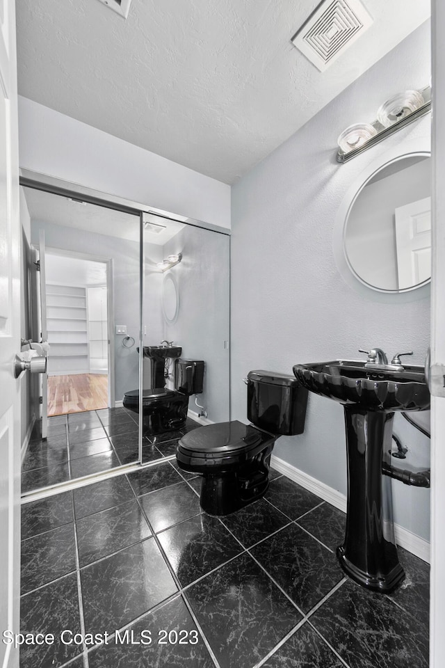 105 Osprey Ct, Melbourne, FL 32940 - bathroom featuring marble look tile flooring, toilet, baseboards, and a textured ceiling
