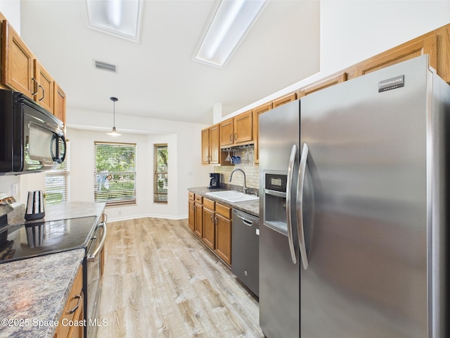187 S Wimbrow Dr, Sebastian, FL 32958 - kitchen with stainless steel appliances, a sink, light wood finished floors, brown cabinetry, and decorative backsplash