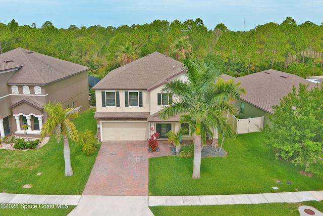 1403 Musgrass Cir, West Melbourne, FL 32904 - view of front of property with decorative driveway, an attached garage, a wooded view, and stucco siding