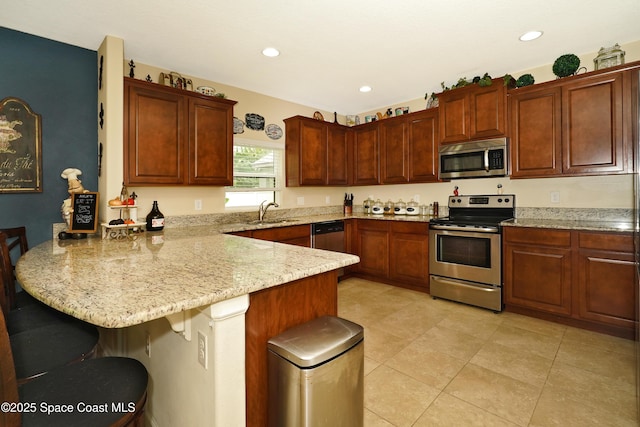 1403 Musgrass Cir, West Melbourne, FL 32904 - kitchen with appliances with stainless steel finishes, a peninsula, a sink, a breakfast bar, and light stone counters