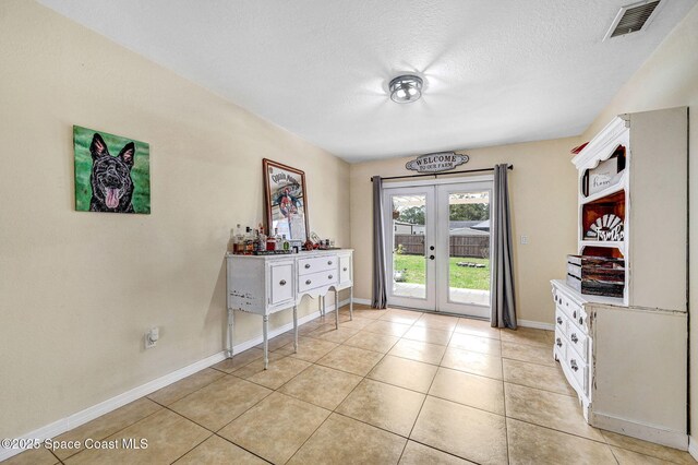 946 Stage St SE, Palm Bay, FL 32909 - doorway to outside with french doors, light tile patterned flooring, a textured ceiling, and baseboards