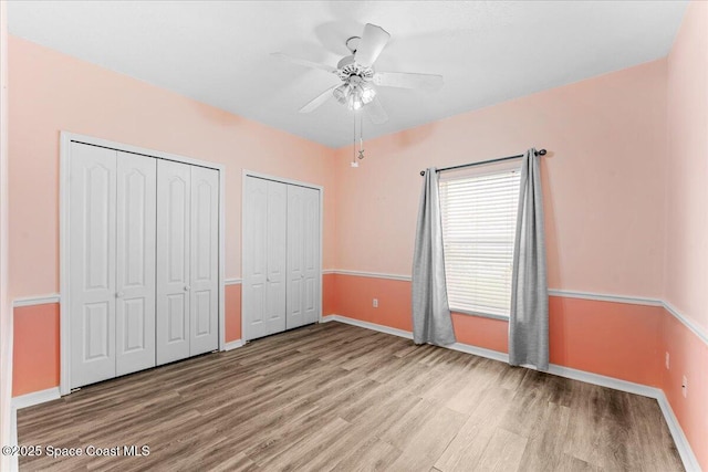 990 Harbor Pines Dr, Merritt Island, FL 32952 - unfurnished bedroom with multiple closets, wood finished floors, baseboards, and a ceiling fan