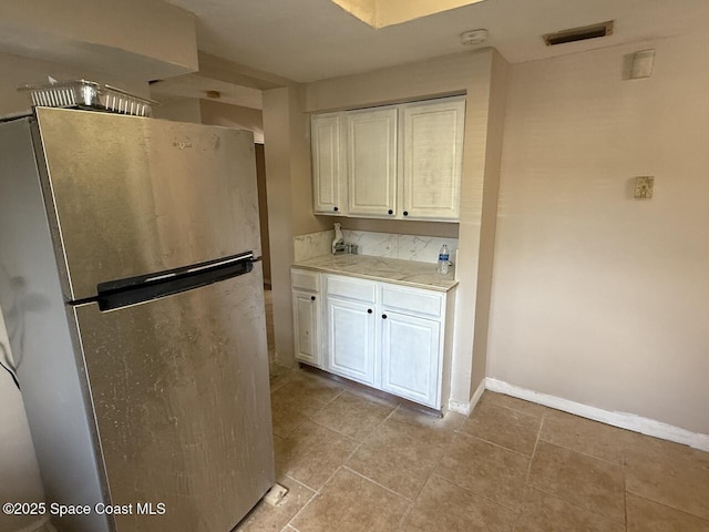 600 Byron Ave, Daytona Beach, FL 32114 - kitchen featuring freestanding refrigerator, light countertops, white cabinets, and baseboards