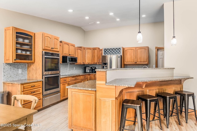 4027 Secretariat Ln, Malabar, FL 32950 - kitchen with stainless steel appliances, a warming drawer, a kitchen breakfast bar, glass insert cabinets, and light wood finished floors
