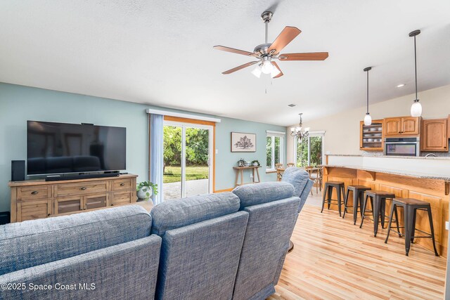 4027 Secretariat Ln, Malabar, FL 32950 - living area featuring plenty of natural light, vaulted ceiling, light wood-style floors, ceiling fan, and a chandelier