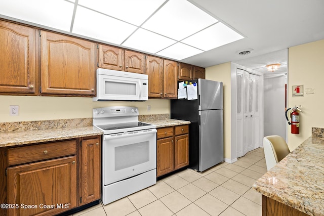 3170 N Atlantic Ave Unit 407, Cocoa Beach, FL 32931 - kitchen featuring white appliances, light tile patterned floors, and brown cabinetry