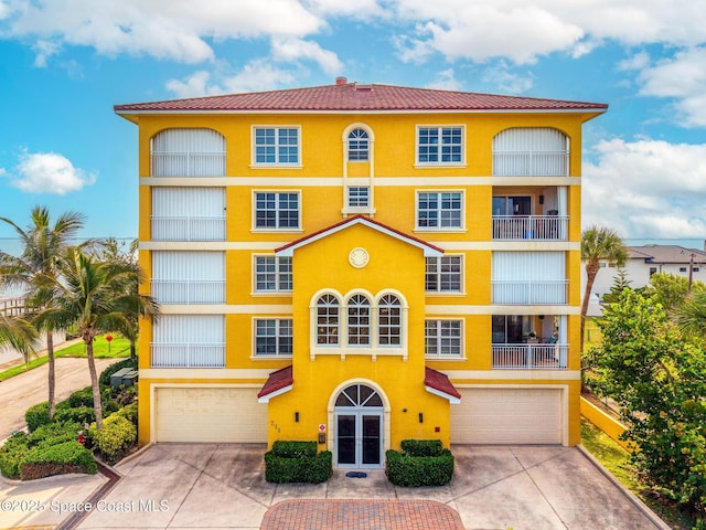 211 S 24th St Unit 202, Cocoa Beach, FL 32931 - view of front of home featuring an attached garage, concrete driveway, stucco siding, and french doors