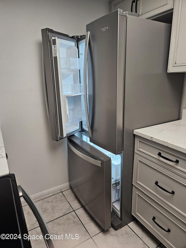 230 Columbia Dr Unit 213, Cape Canaveral, FL 32920 - kitchen with gray cabinets, light stone counters, baseboards, light tile patterned flooring, and freestanding refrigerator