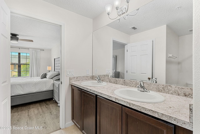 1415 Lara Cir Unit 105, Rockledge, FL 32955 - bathroom featuring ensuite bathroom, double vanity, a textured ceiling, wood finished floors, and a chandelier