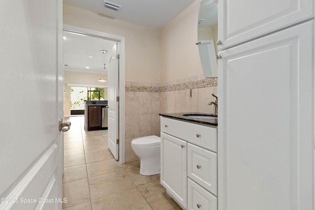 3140 Constellation Dr, Melbourne, FL 32940 - bathroom with vanity, tile patterned floors, toilet, tile walls, and wainscoting