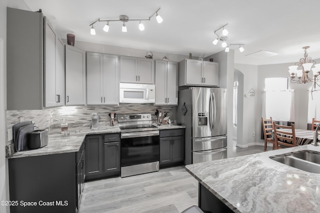4345 Millicent Cir, Melbourne, FL 32901 - kitchen with appliances with stainless steel finishes, gray cabinets, arched walkways, a sink, and decorative backsplash
